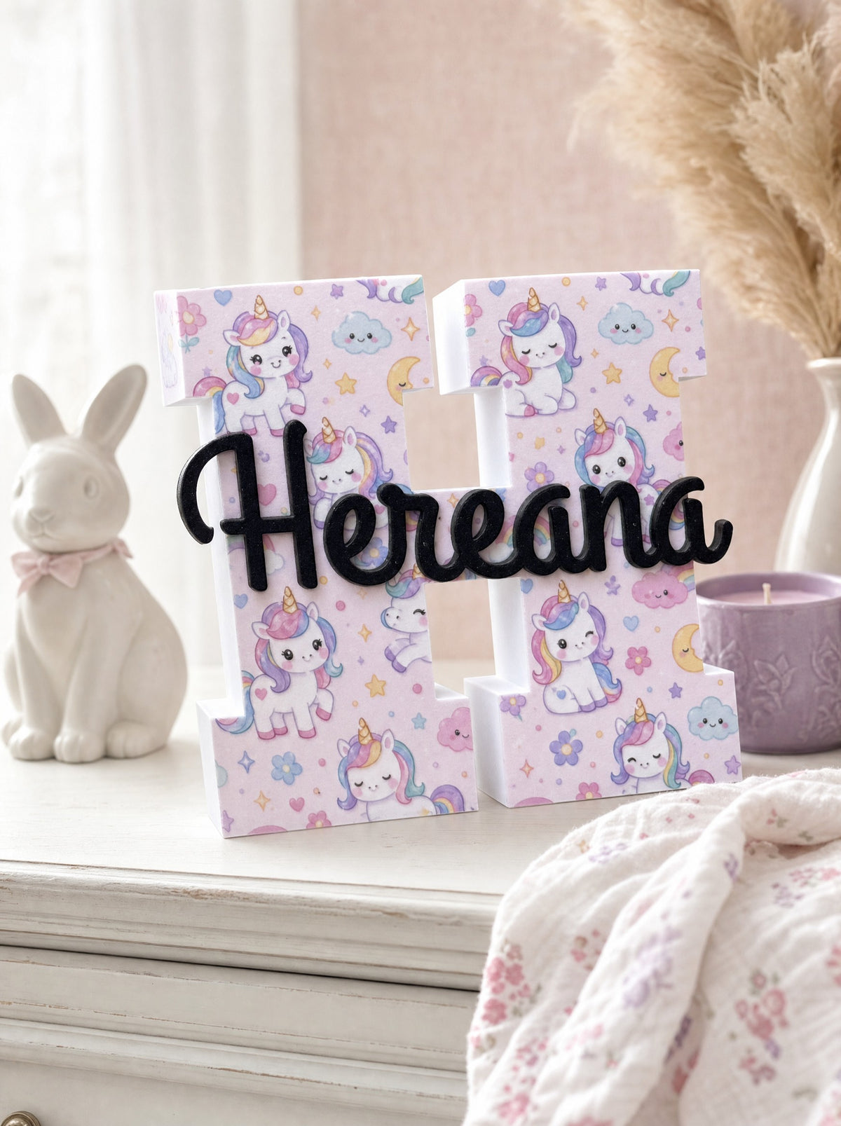 Prénom 3D en relief Hereana, initiale à décor licornes, posé sur une commode de chambre d'enfant